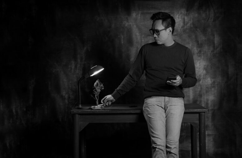 Digital Detox: Mann mit Zigarette sieht auf sein Smartphone